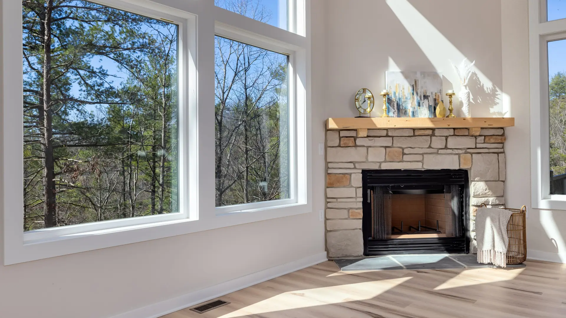 A living room with a stone fireplace and tall windows